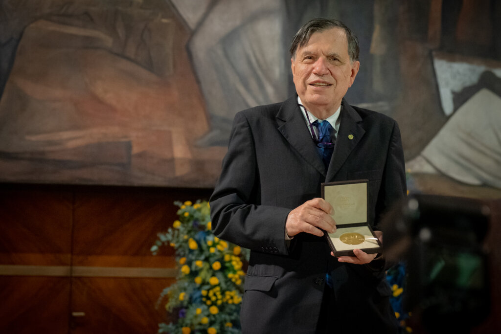 Giorgio Parisi stands holding his Nobel Prize medal.jpg